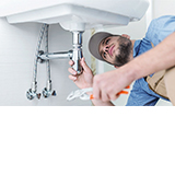 Installateurarbeiten am Waschbecken Am Waschbecken arbeitender Installateur